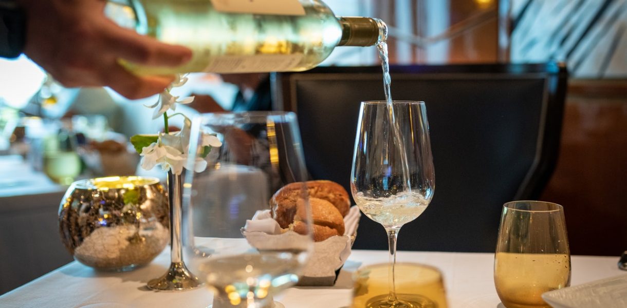 bouteille de pinot gris coulée sur verre à vin posé sur table de restaurant