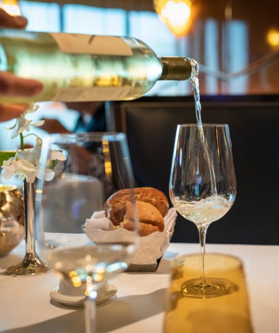 bouteille de pinot gris coulée sur verre à vin posé sur table de restaurant